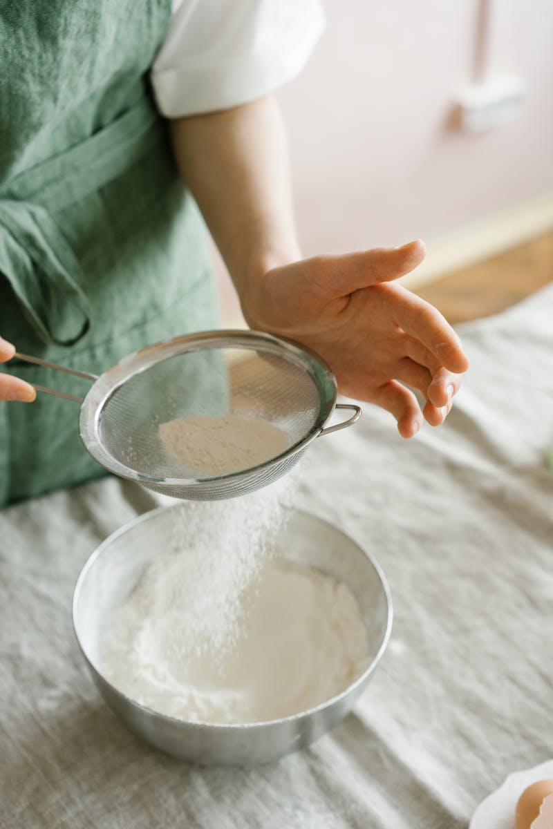 Stainless steel flour sifter sifting flour into a bowl